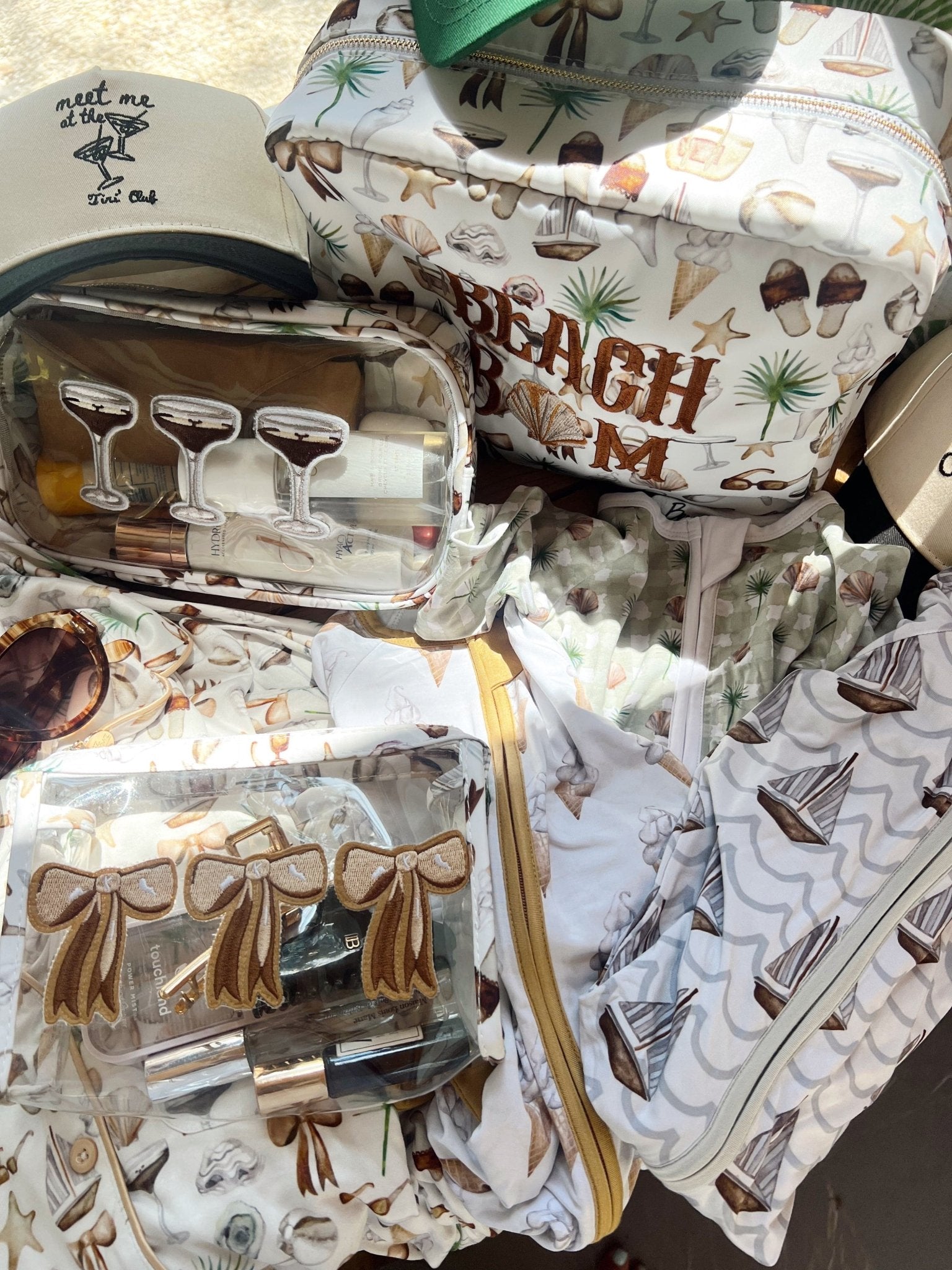 Neutral coastal print travel organizer bag with cocktail glass design, gold trim, and interior pockets displaying drinkware and party supplies.