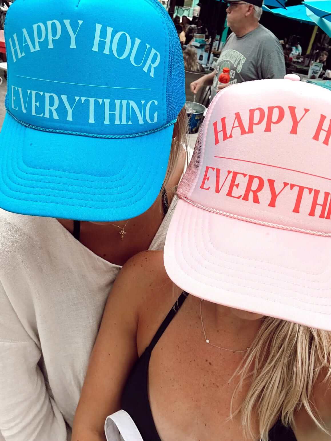 Bright blue and pink trucker hats with "Happy Hour Everything" text printed in white and red lettering.