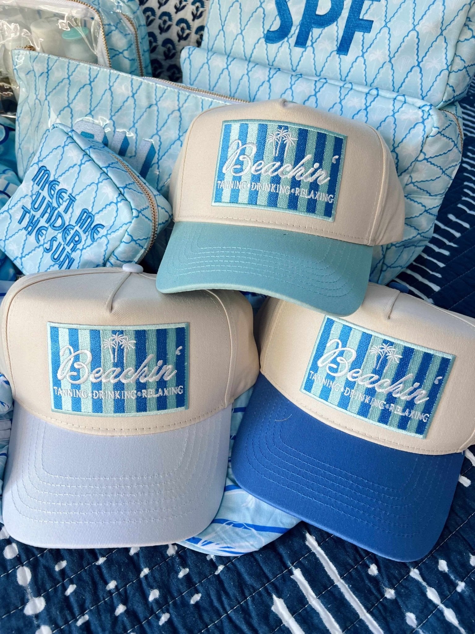 Three vintage trucker hats in blue and white colorways with "Beachin'" text and striped patches on the front panels.