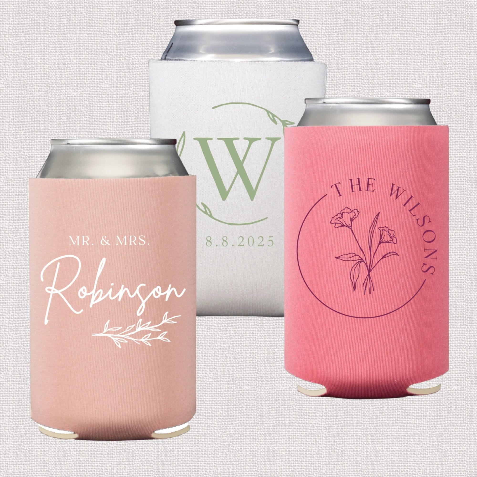 Three wedding can coolers in blush, white, and coral pink with personalized monogram, floral, and script text designs