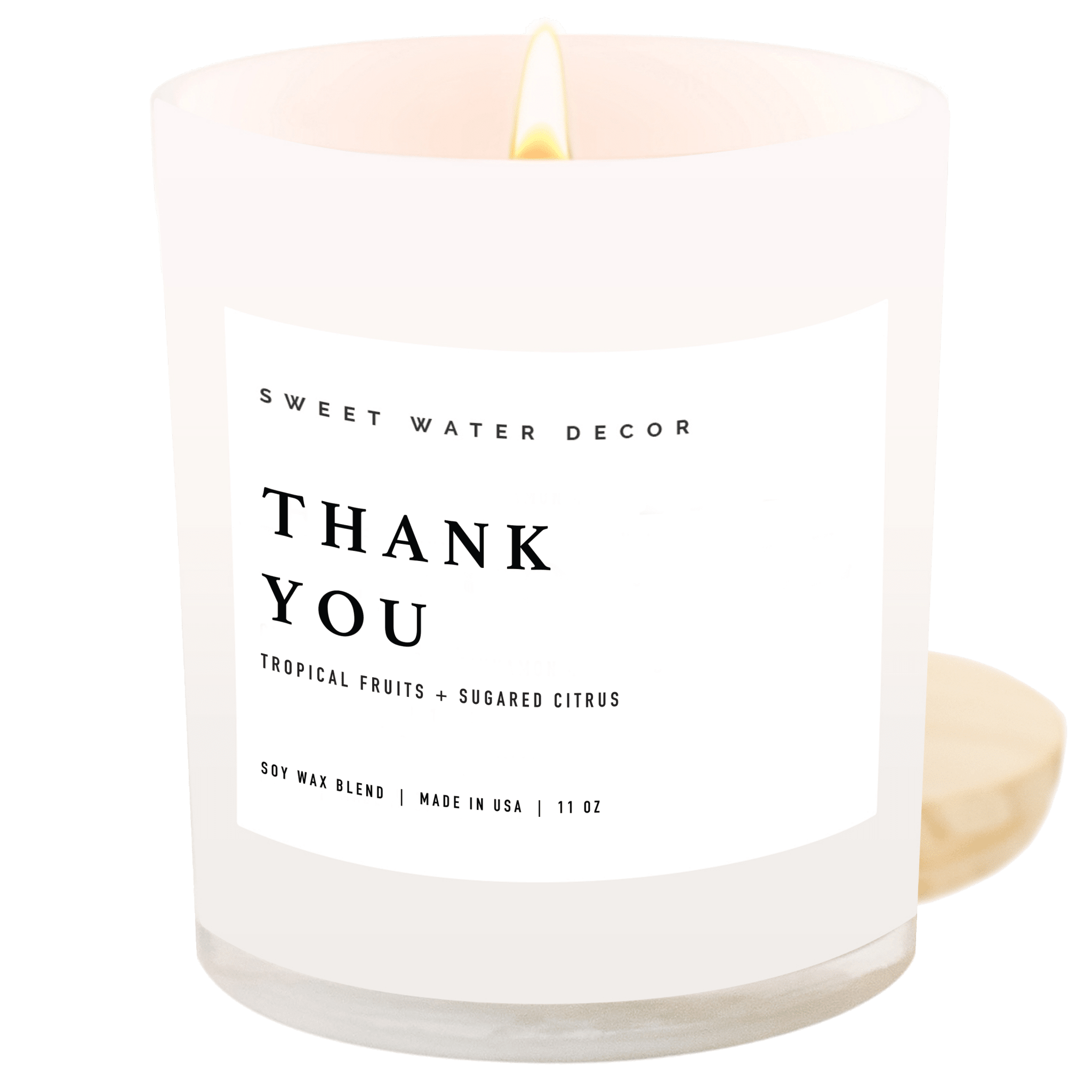 White soy candle with "THANK YOU" text and tropical fruits plus sugared citrus scent label, 11 oz jar with lit flame.