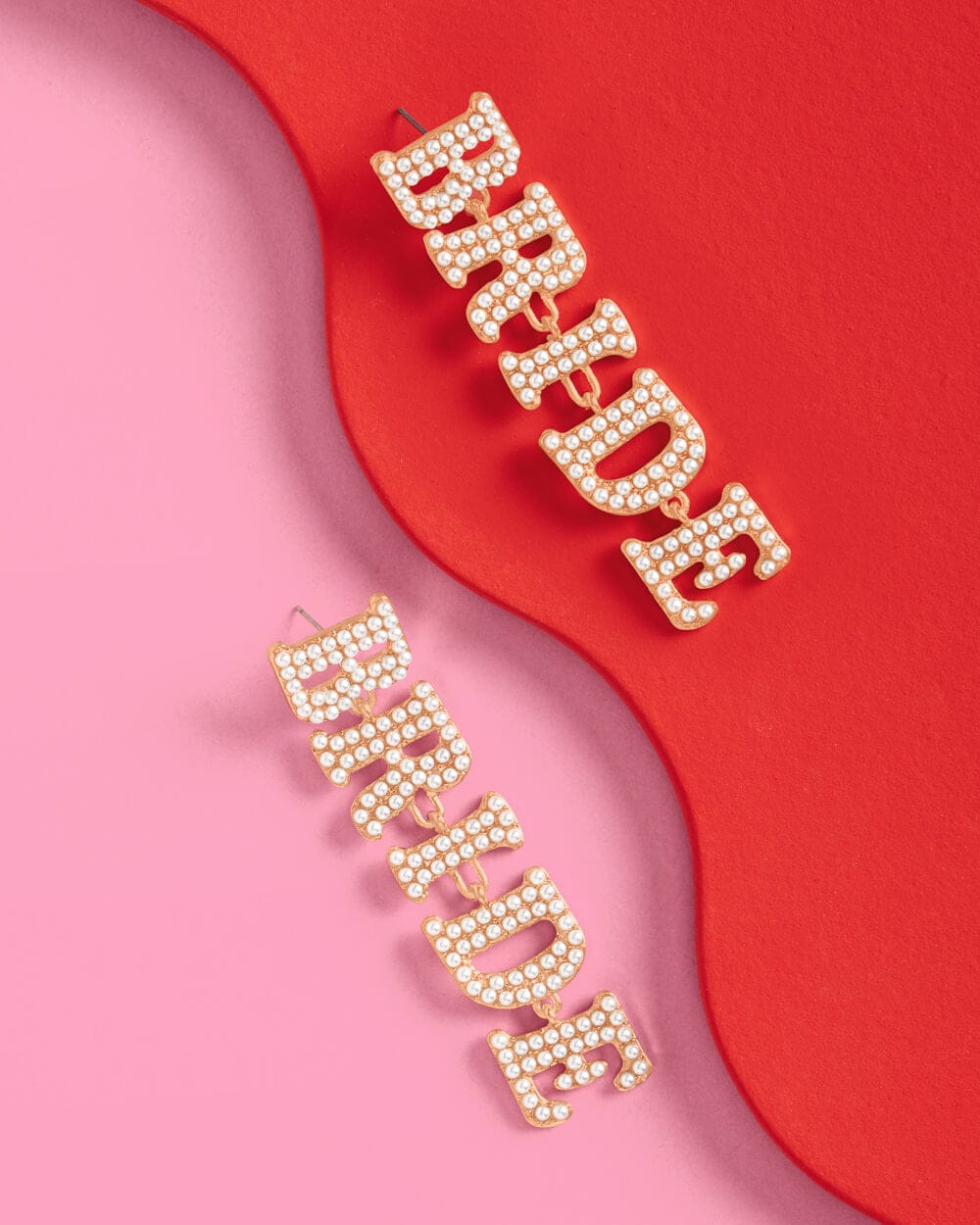 Pearl drop earrings spelling "Bride" and "Bridesmaid" on red and pink curved backgrounds