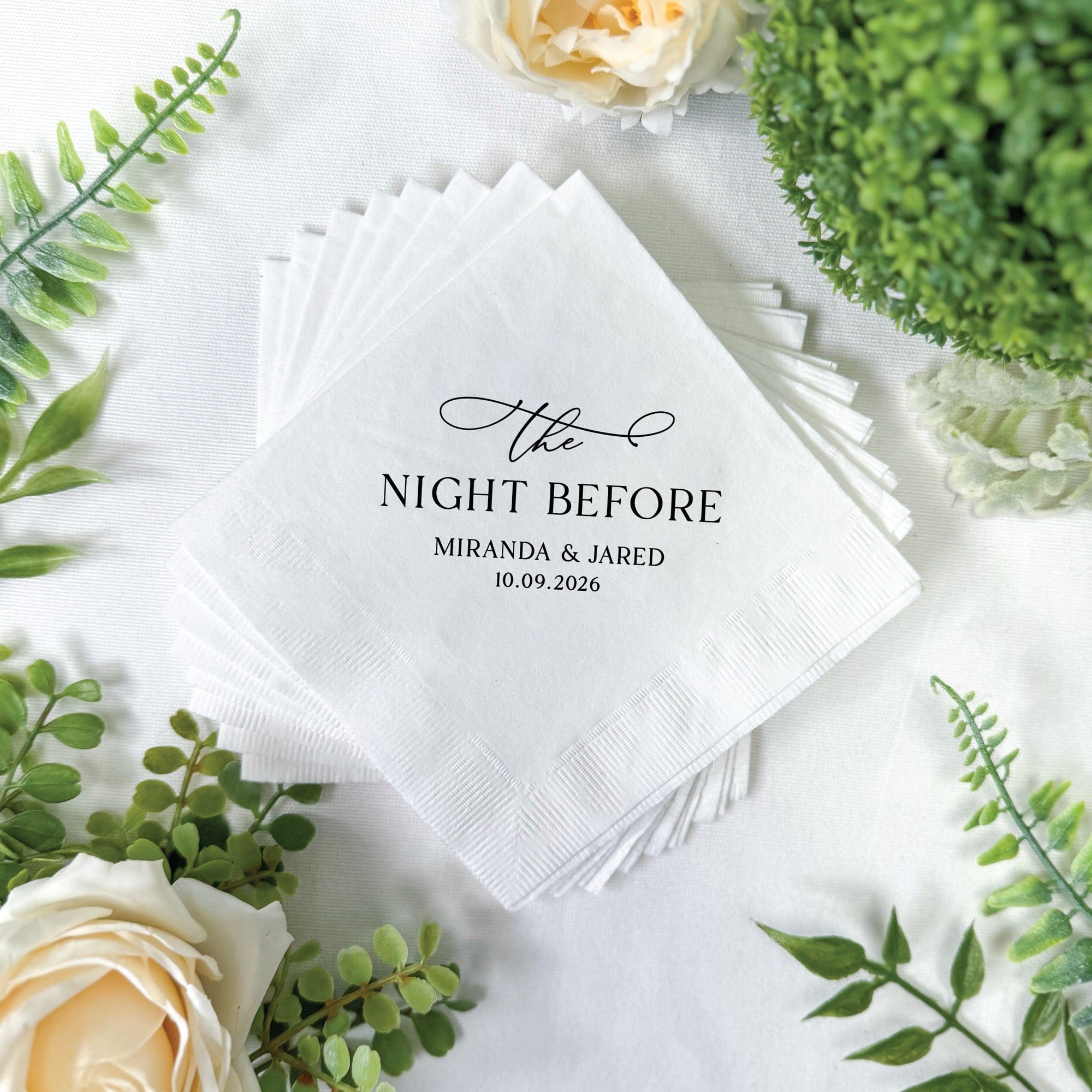 A stack of white paper napkins, custom-printed with a black design, featuring embossed borders, suitable for a wedding or pre-wedding celebration.