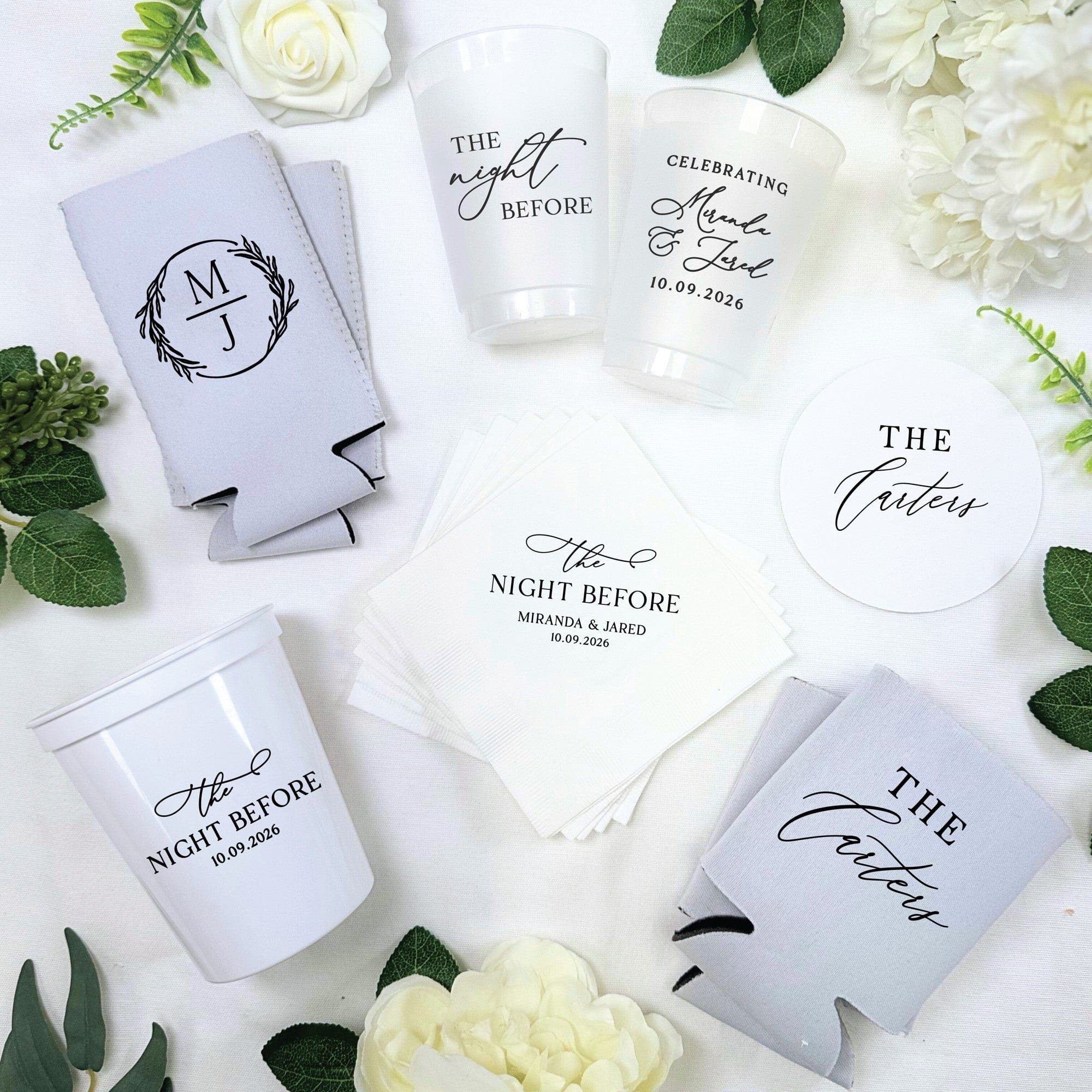 A personalized wedding event decor bundle includes light gray neoprene can coolers, white plastic cups, white paper cocktail napkins, and white round paper coasters, all custom-printed with elegant designs.