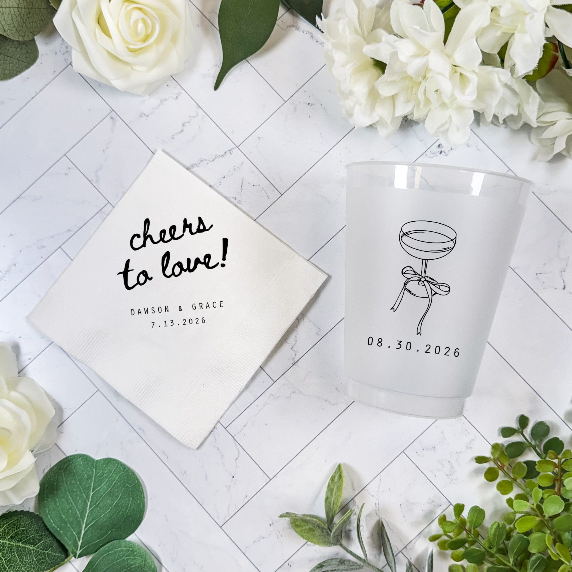 This personalized wedding decor set features a white folded paper napkin and a frosted plastic cup, ideal for serving celebratory drinks at a special event.