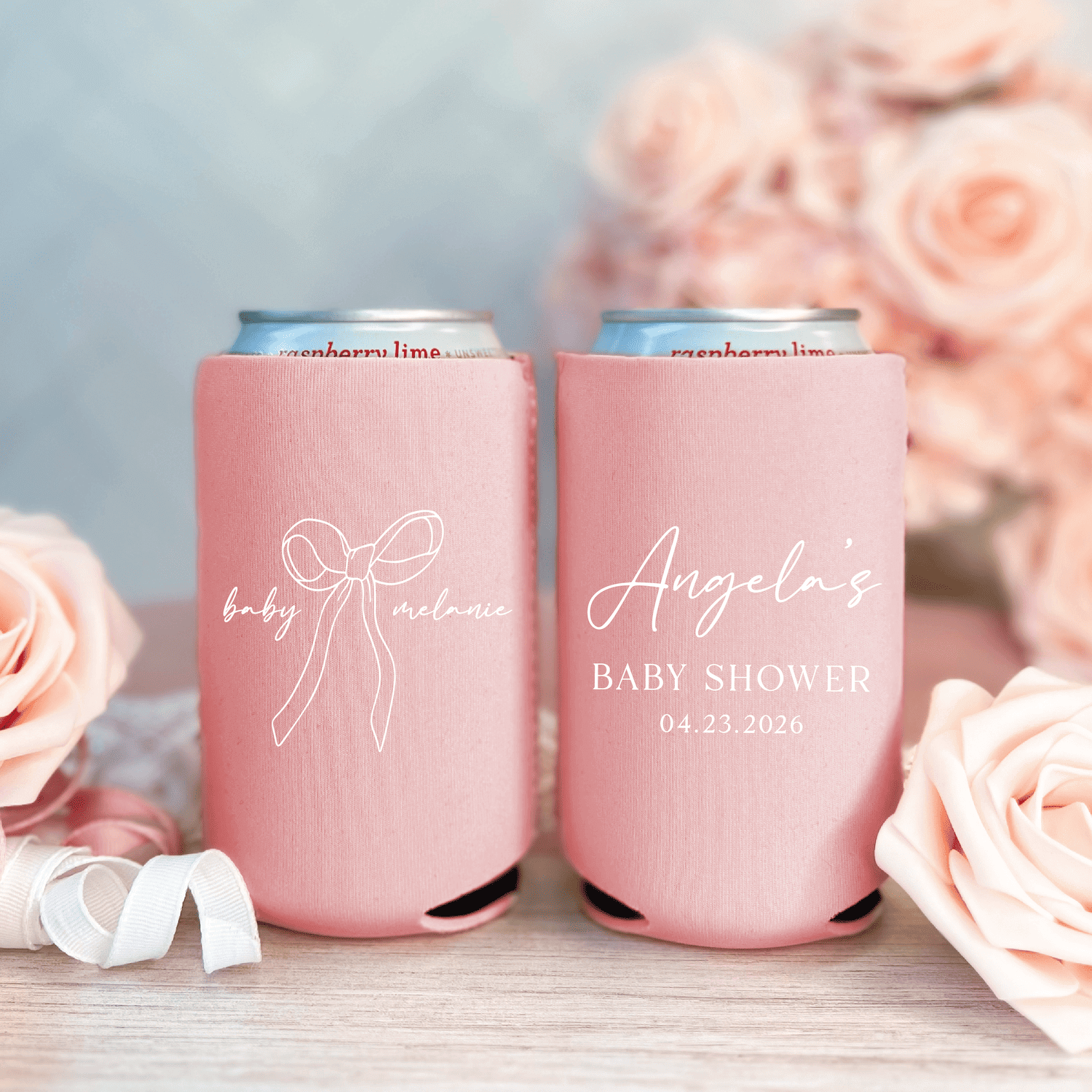 Pink can coolers with "baby shower" bow design and "Angel's" personalized text dated 04.23.2024, surrounded by blush roses
