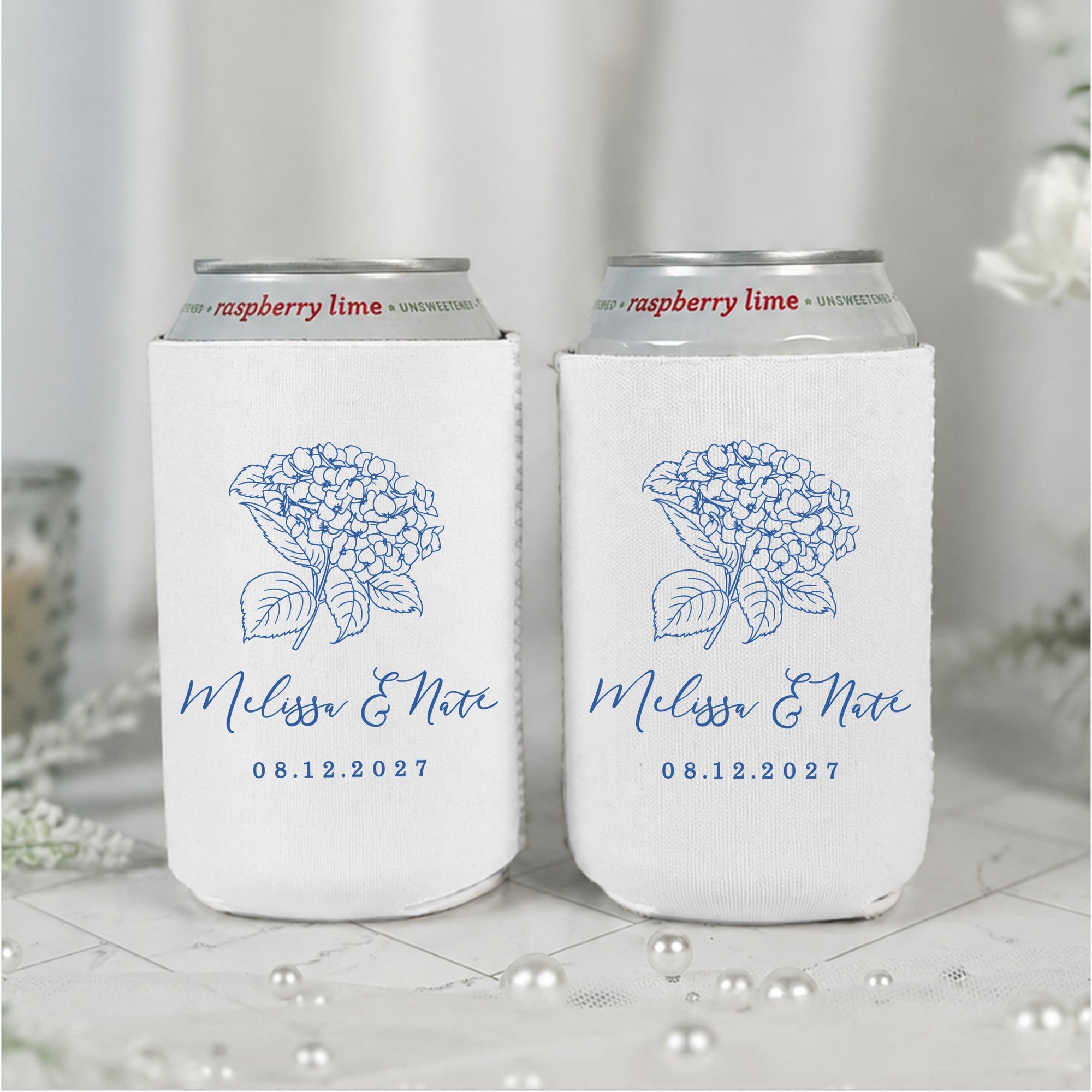 Two white insulating can coolers, each featuring a classic blue hydrangea floral design, are perfect personalized wedding favors or event decor.
