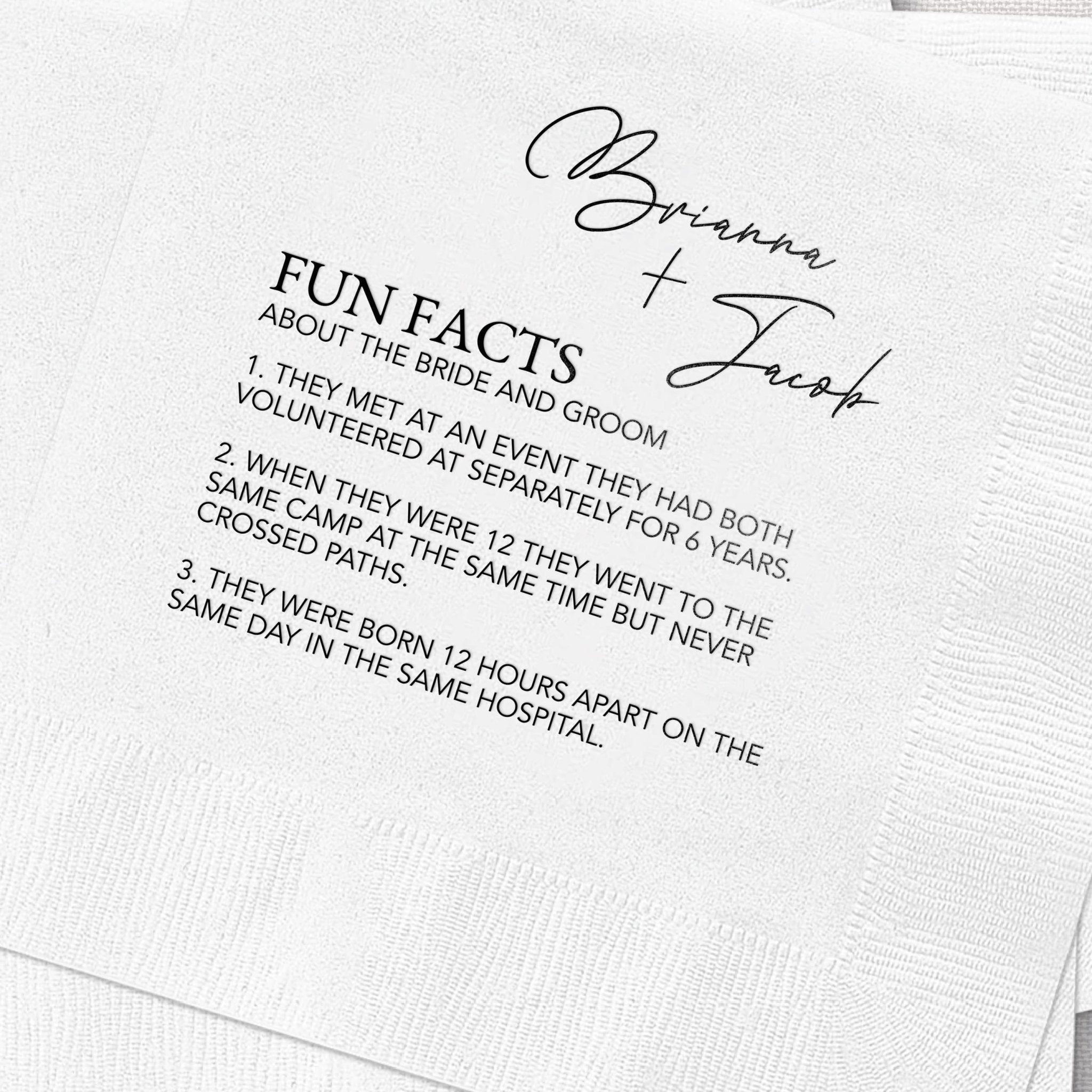 White napkin with black foil-stamped text reading "Brianna + Zach" and "Fun Facts About the Bride and Groom" followed by numbered trivia points.