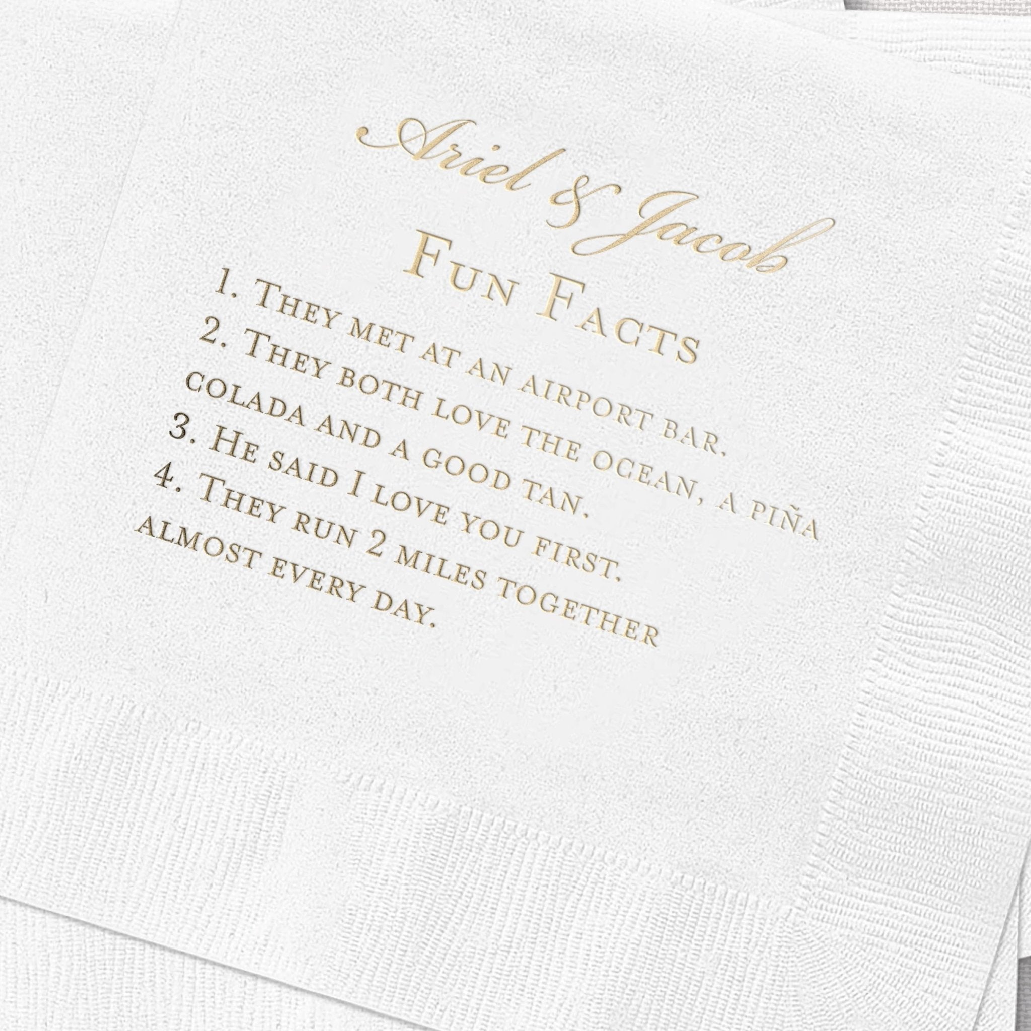 White cocktail napkin with gold foil stamped text reading "Abel & Jacob Fun Facts" and five personalized fun facts about the couple in elegant script font.
