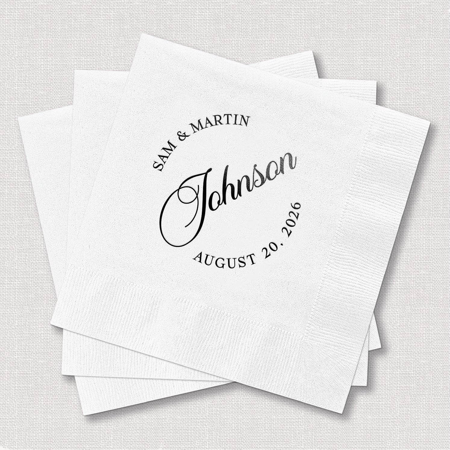 Stack of personalized white cocktail napkins with modern monogram wedding design printed with couple's names