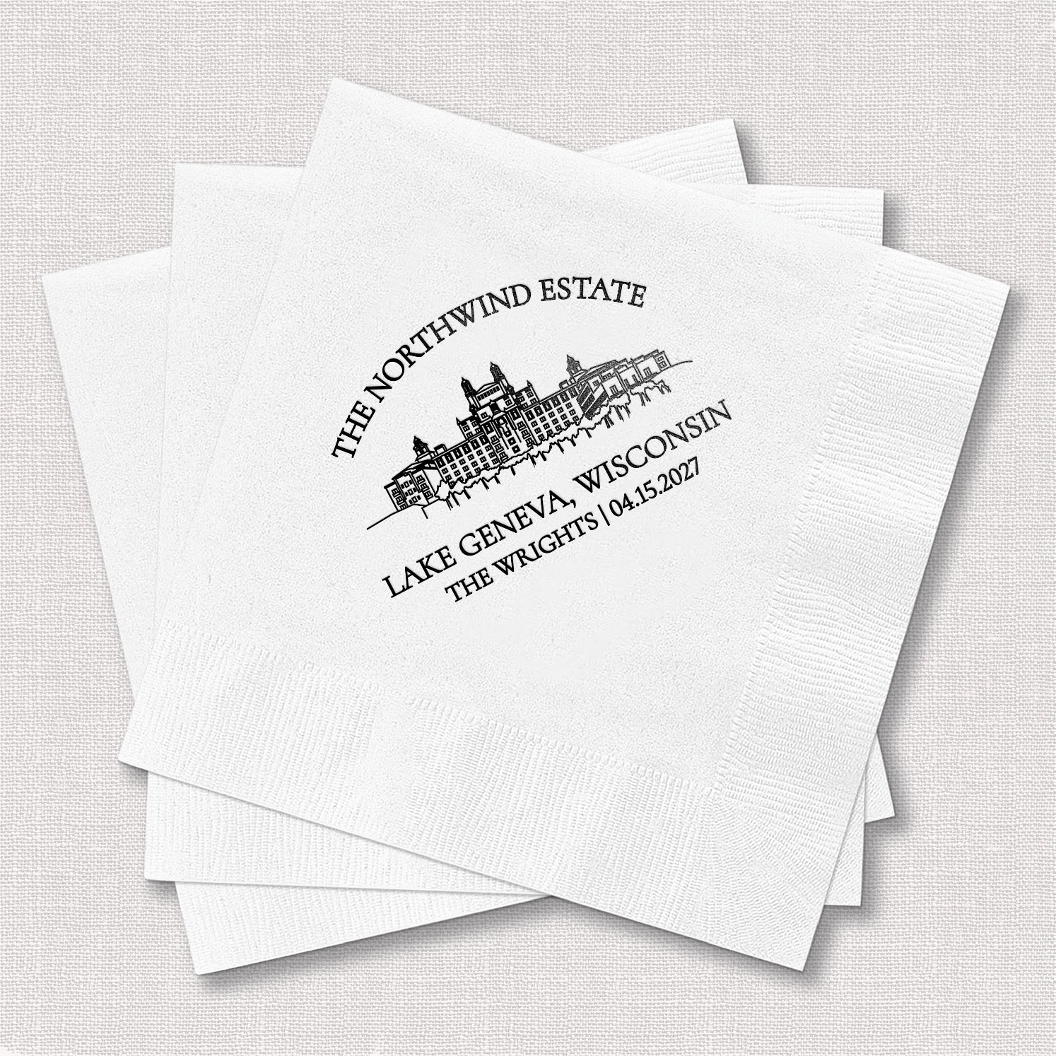 Stack of personalized white cocktail napkins with venue line drawing wedding design printed with couple's initials and venue details