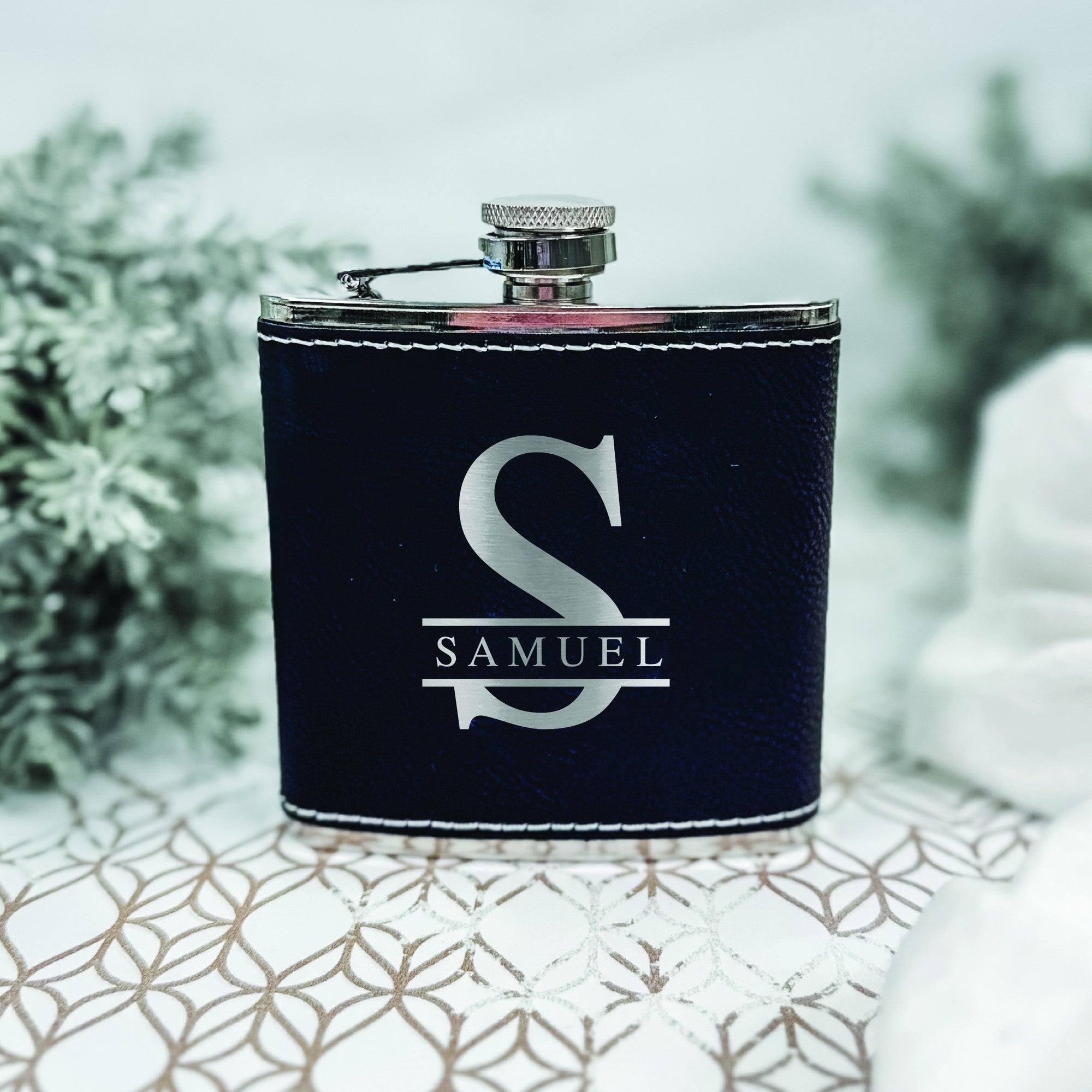 A dark blue faux leather-wrapped metal flask with a silver-tone screw-top cap, featuring a personalized engraved design, ideal for groomsmen or special occasion gifting.