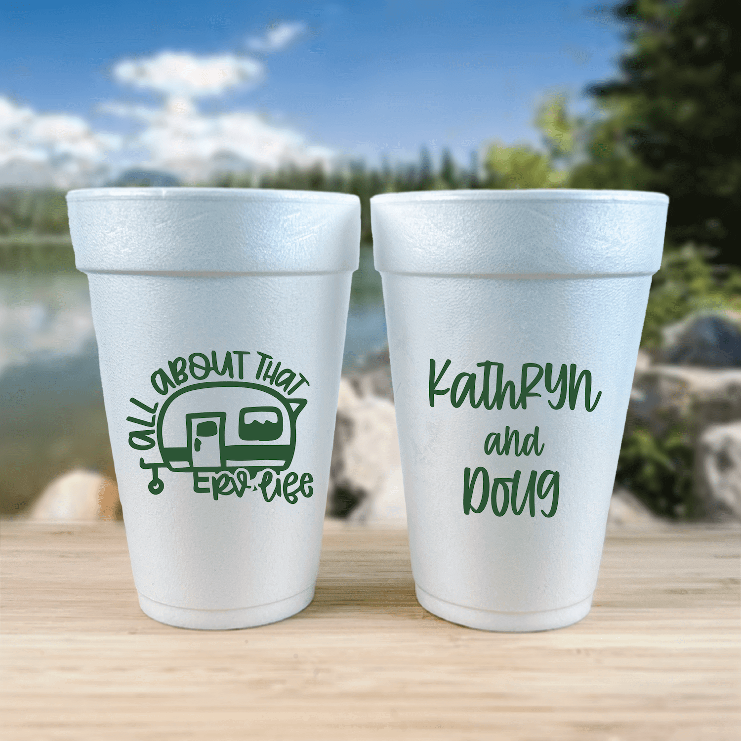 Two white foam cups with green text, one reading "All About That RV Life" with camper icon, the other personalized "Kathrun and Doug"