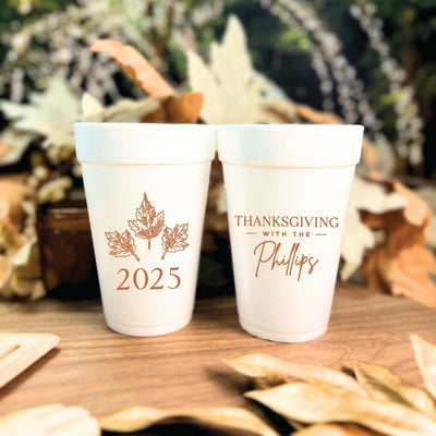 Two white foam cups feature autumn leaf illustrations and customized typography, perfect for fall season gatherings.