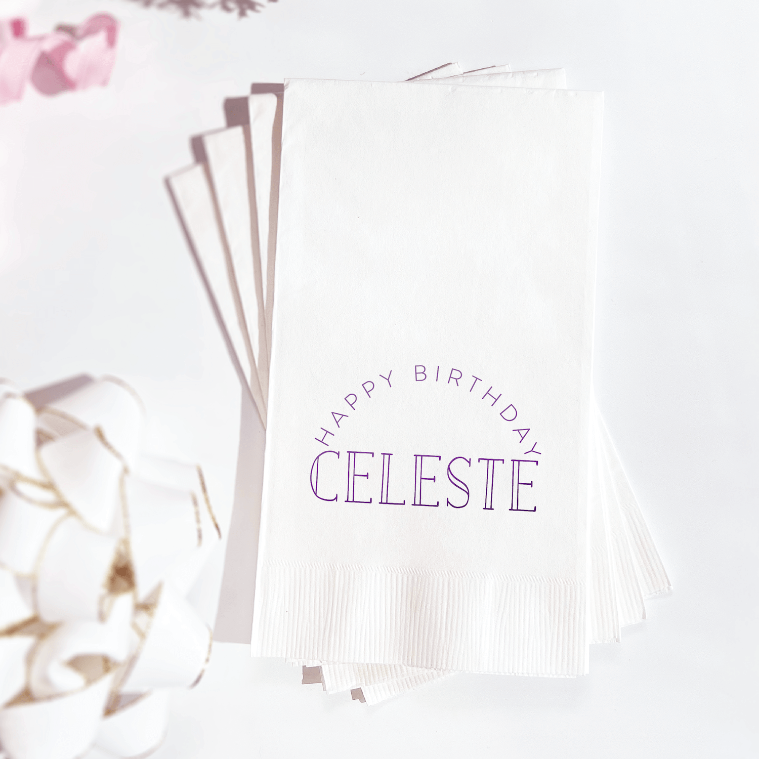 White napkins with purple foil-stamped "Happy Birthday Celeste" text, fanned display with dried flowers