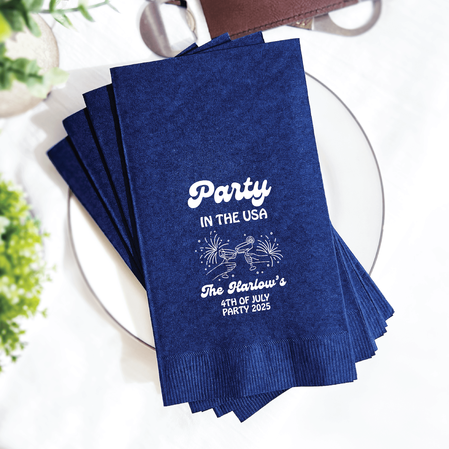Stack of navy blue napkins with white foil-stamped text reading "Party in the USA" and "The Harlow's 4th of July Party"