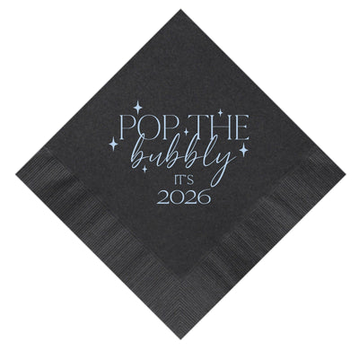 A dark gray folded paper napkin with a light blue graphic design featuring starburst accents, suitable for a festive occasion.