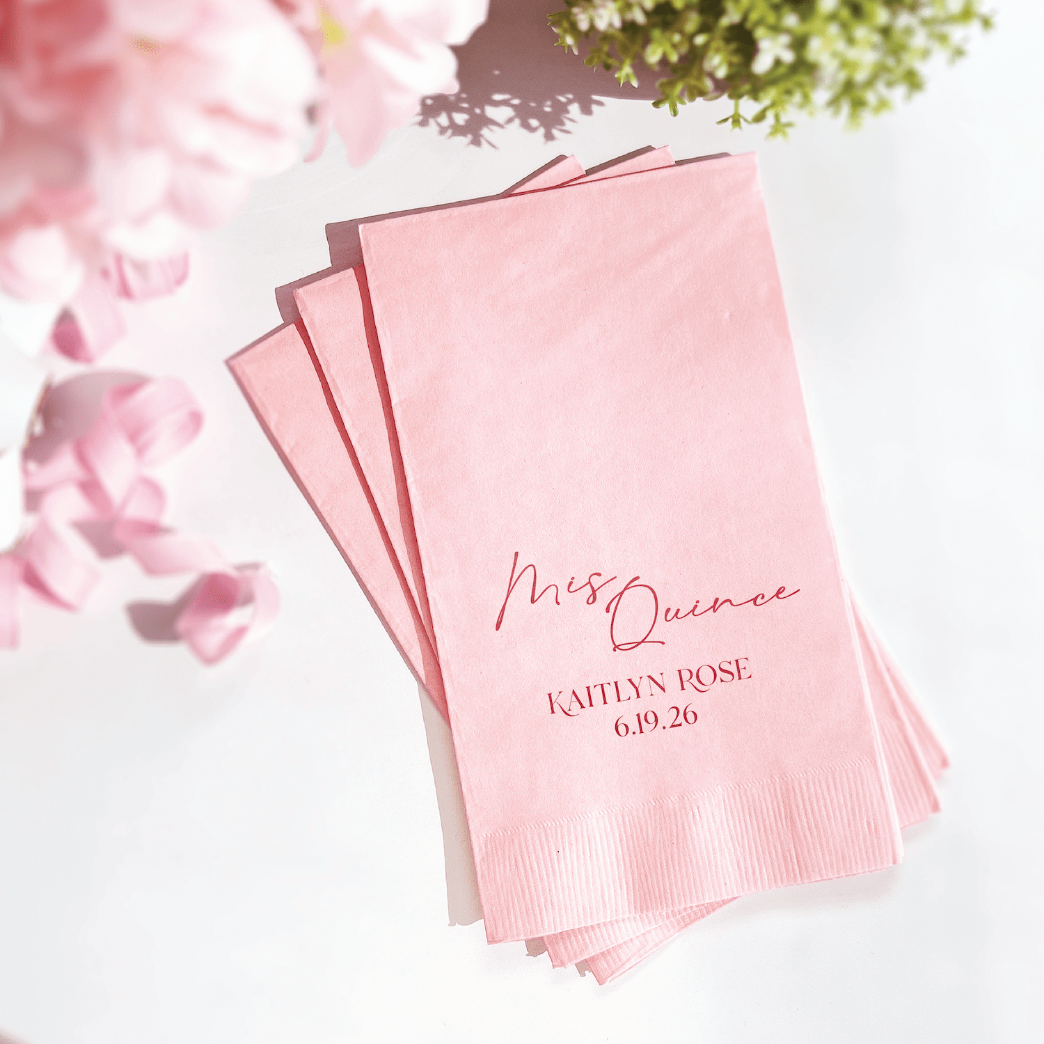 Stack of blush pink napkins with rose gold foil stamped "Mis Quince" script and personalized name with date.