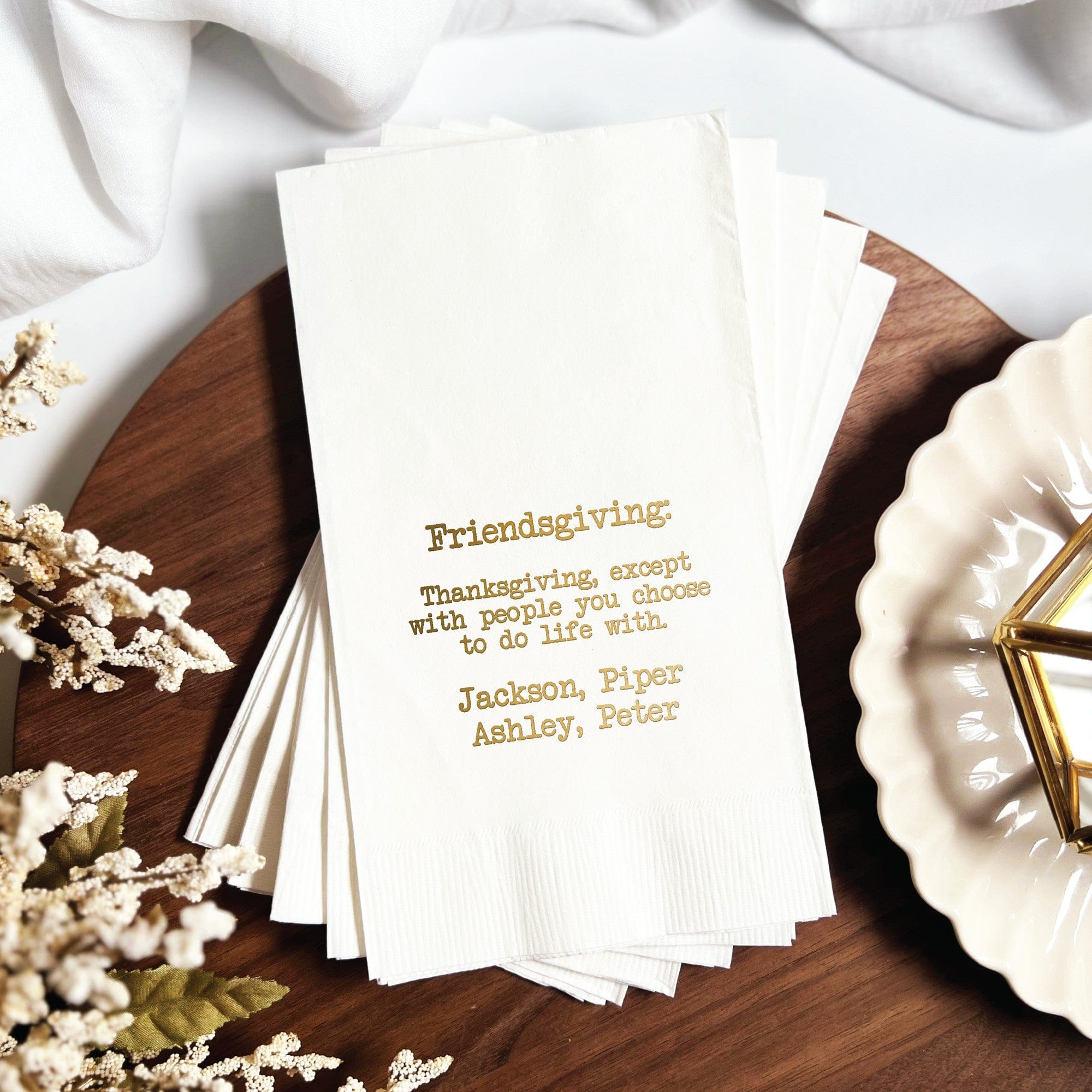 A stack of white paper napkins featuring custom gold foil printing, suitable for a special gathering.