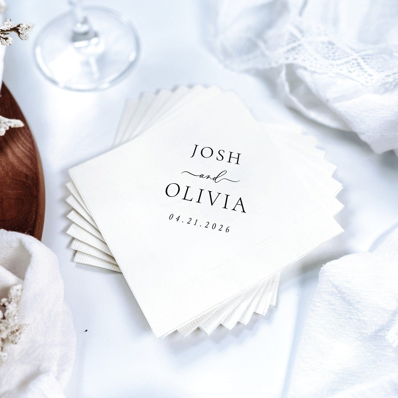 A stack of white paper wedding napkins with a textured surface, elegantly personalized with custom black typography for a special event.
