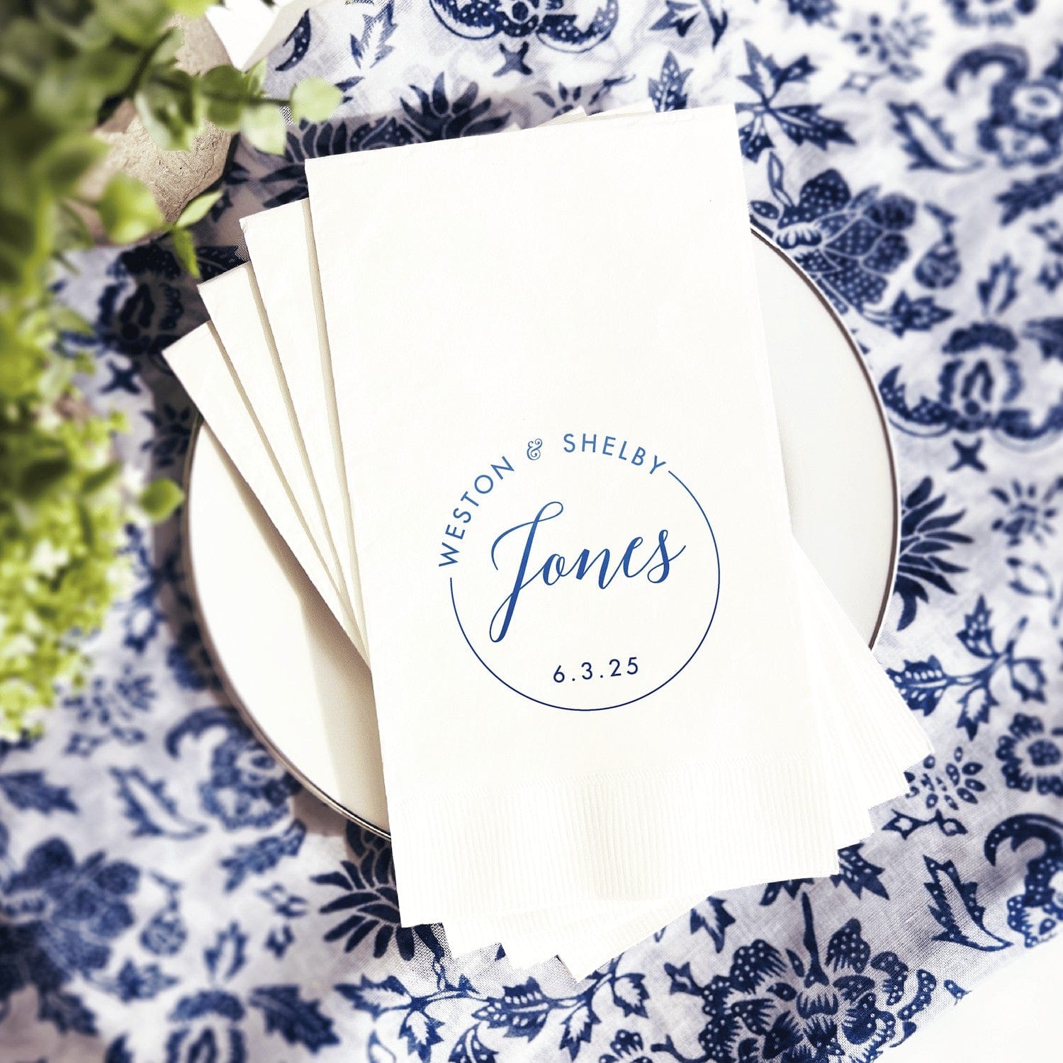 A stack of elegant white paper napkins customized with a blue circular design, perfect for a wedding or special event.