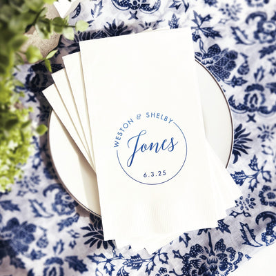 A stack of elegant white paper napkins customized with a blue circular design, perfect for a wedding or special event.