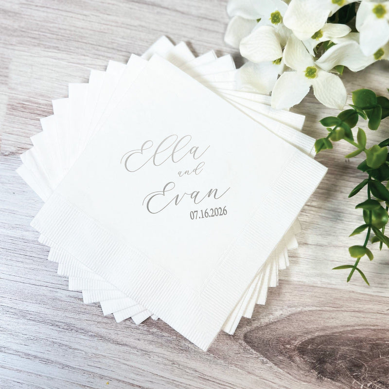 A stack of white paper wedding napkins, personalized with custom text in a gray script font for event decor.