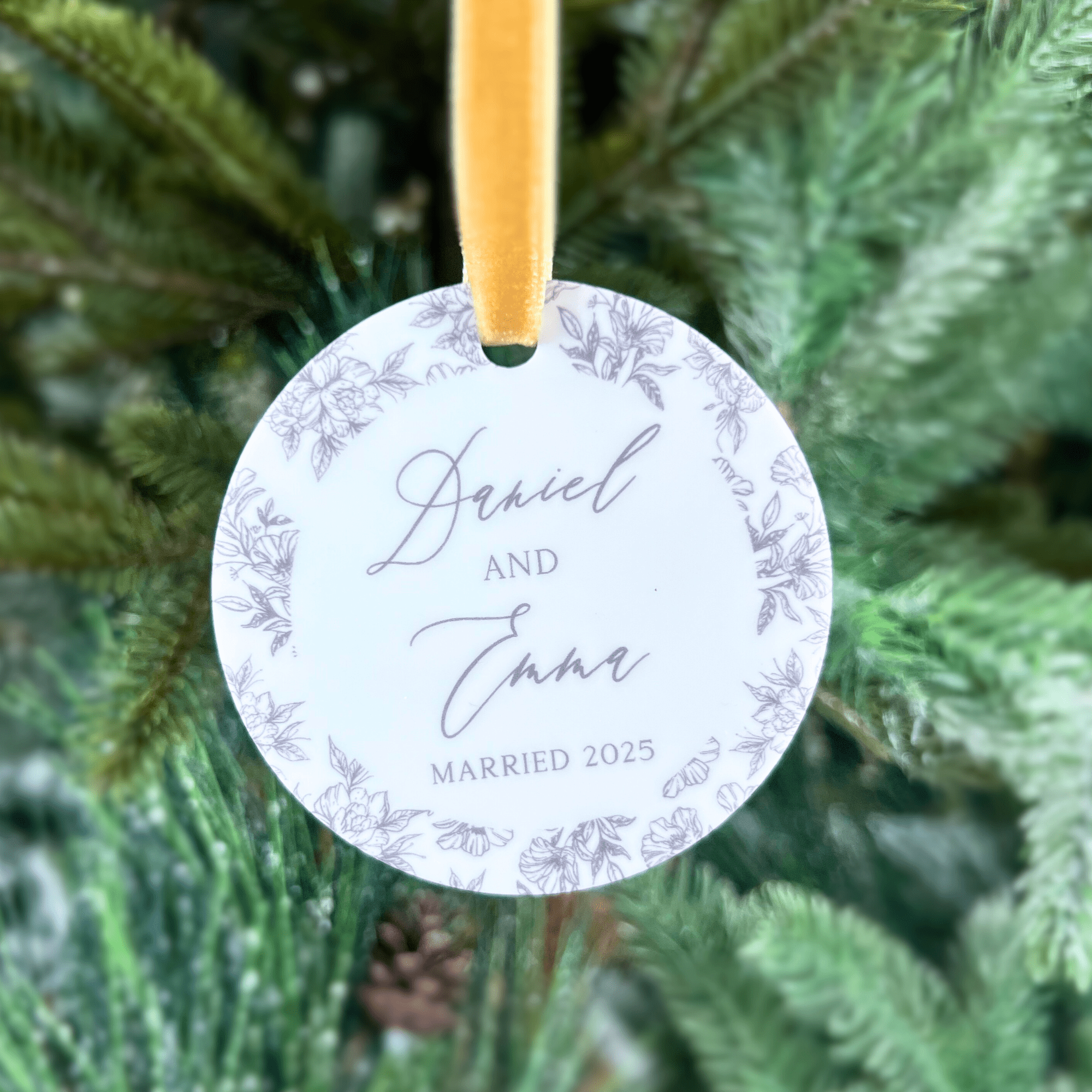 Round acrylic ornament with gold ribbon, featuring names "Darvel and Jane" with "Married 2025" and purple floral toile border design.