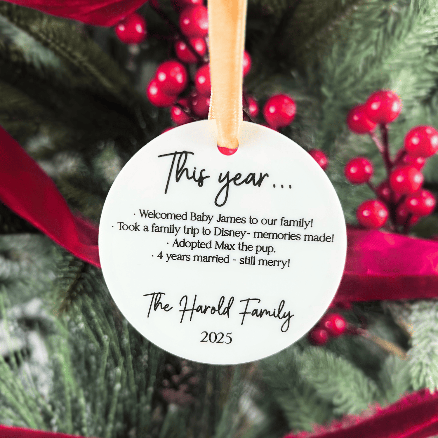 White round acrylic ornament with handwritten-style text reading "This year..." and family highlights including new baby and Disney trip, signed "The Harold Family 2023"