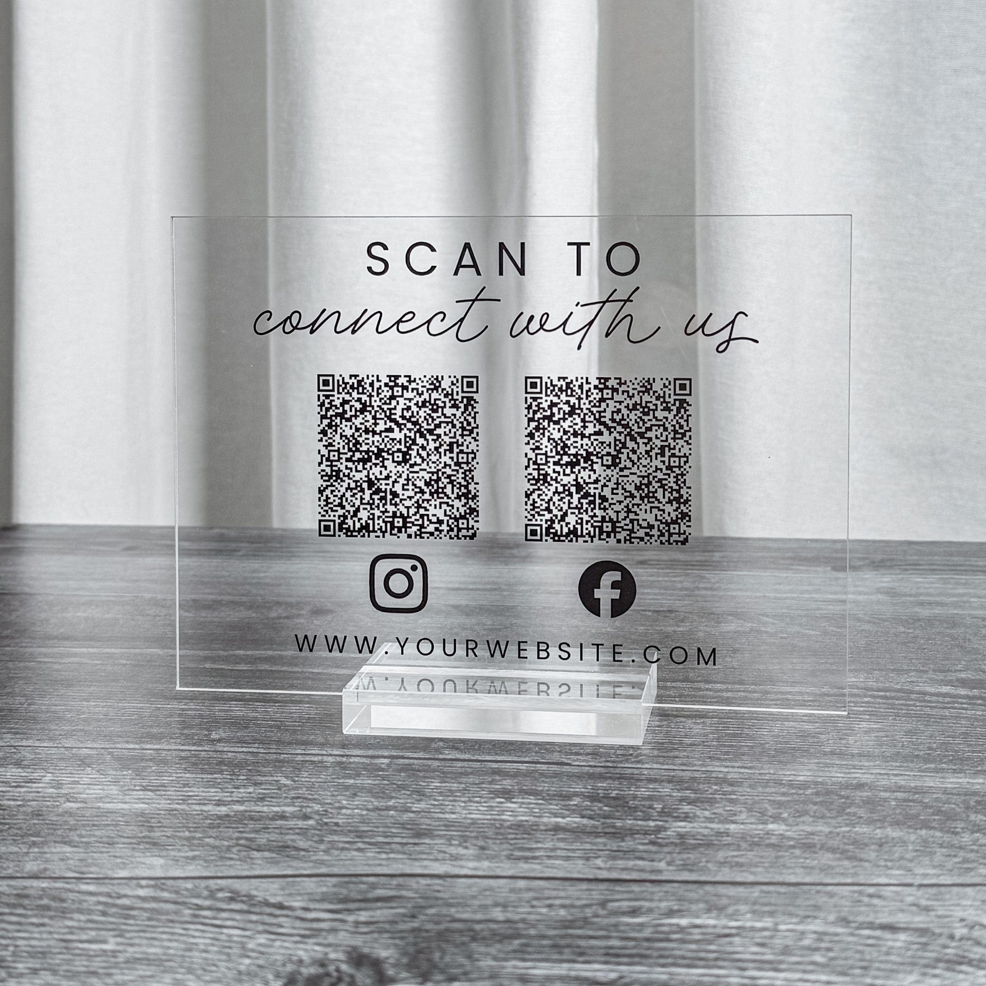A clear acrylic wedding and event sign featuring two black QR codes and social media icons, designed for guests to easily connect digitally.