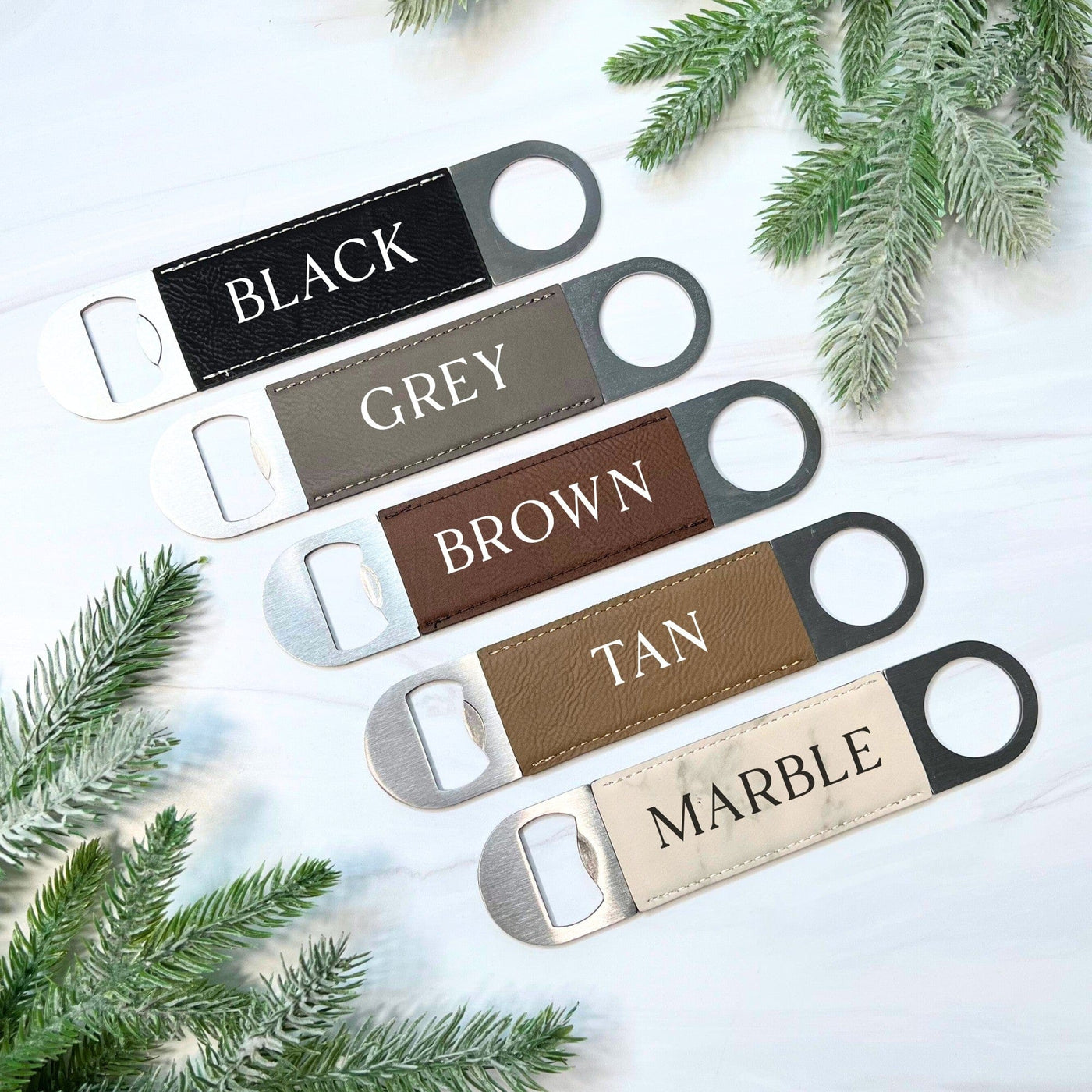 Five personalized bottle openers are showcased, featuring a brushed silver metal end and faux leather handles in black, grey, brown, tan, and a cream-colored marble pattern, perfect for wedding or event decor.