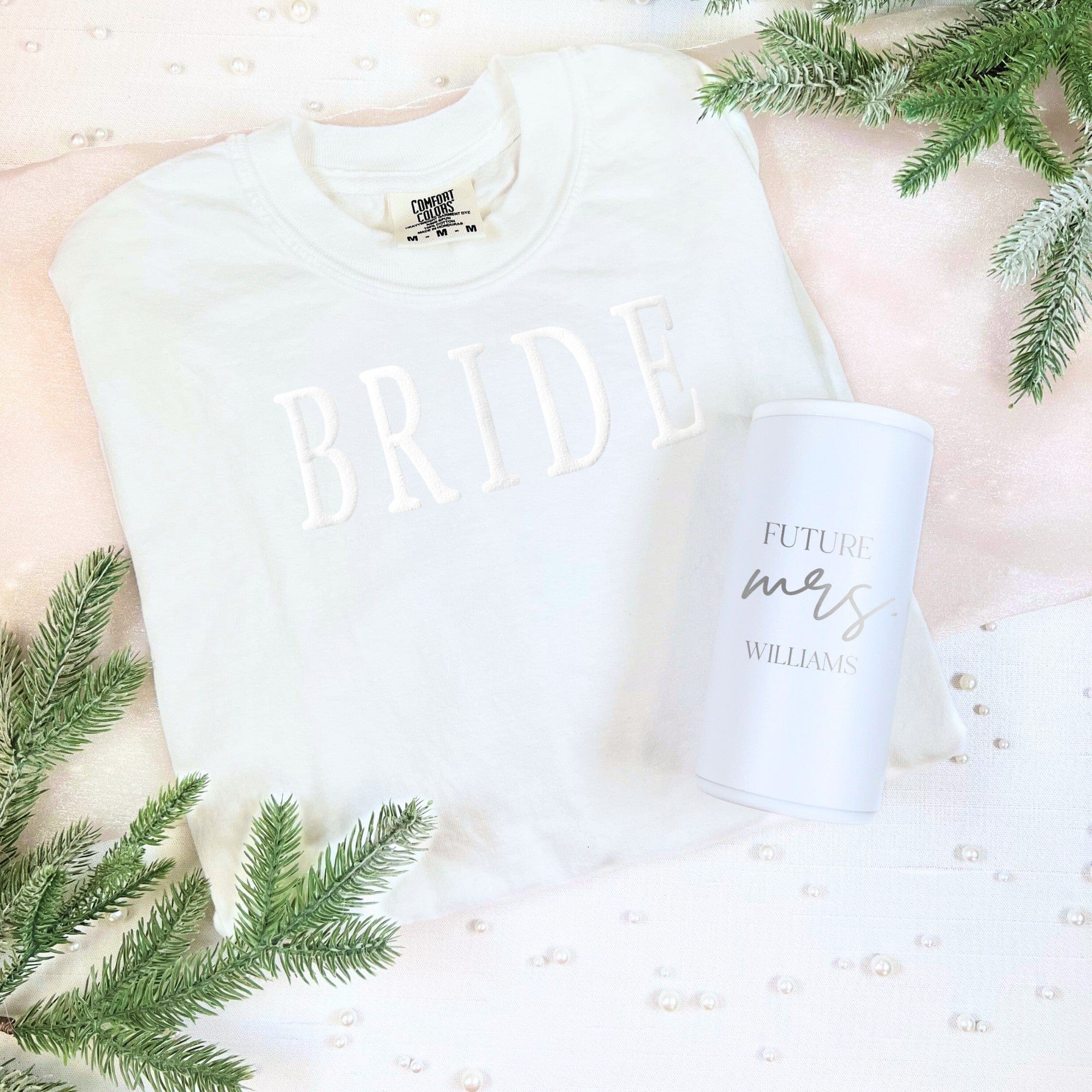 A white embroidered bridal sweatshirt and a matching white insulated tumbler are displayed as a thoughtful gift set for a wedding or bridal shower.