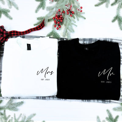 A matching set of a black and a white personalized long-sleeve sweatshirt, made from soft fabric, intended as a thoughtful wedding or engagement gift for a couple.