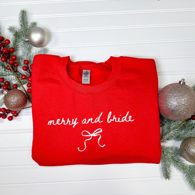 A vibrant red crewneck sweatshirt featuring elegant white embroidery and a bow design, perfect for a festive holiday bridal celebration.