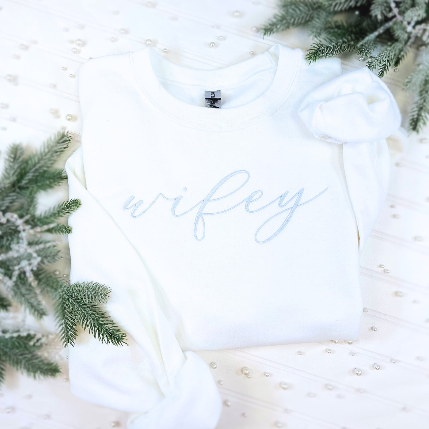 A soft white crewneck sweatshirt with delicate light blue script embroidery, designed for bridal celebrations or a wedding event.