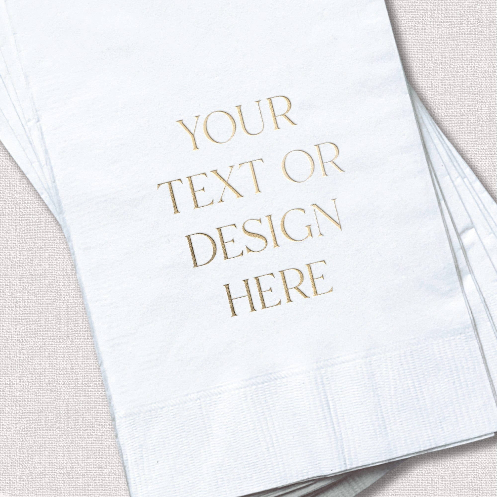 A stack of white disposable paper guest towels or napkins featuring a customizable metallic gold foil design, ideal for wedding receptions or events.