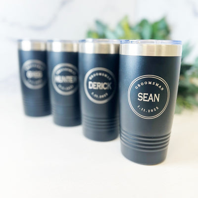 Four black insulated metal tumblers with clear lids are custom engraved with circular designs, perfect for a wedding party.
