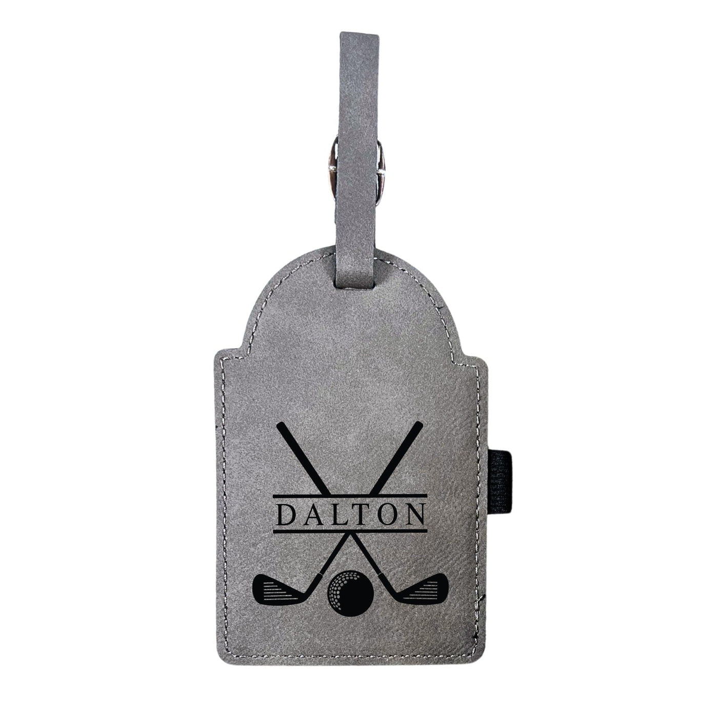 A grey faux leather luggage tag with an arched top features a black engraved design of crossed golf clubs and a golf ball, secured by a strap with a silver buckle, for a personalized travel accessory.