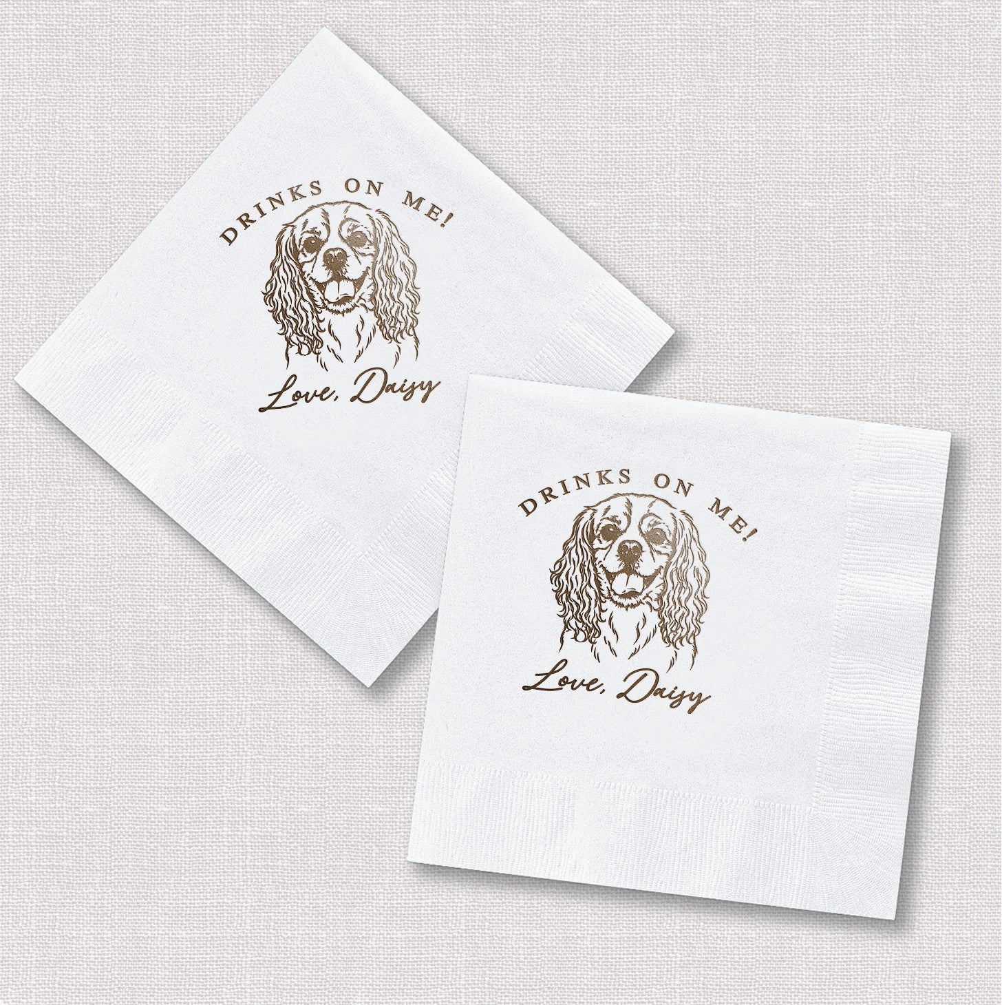 Two personalized white paper beverage napkins featuring a custom brown dog illustration, perfect for an event.
