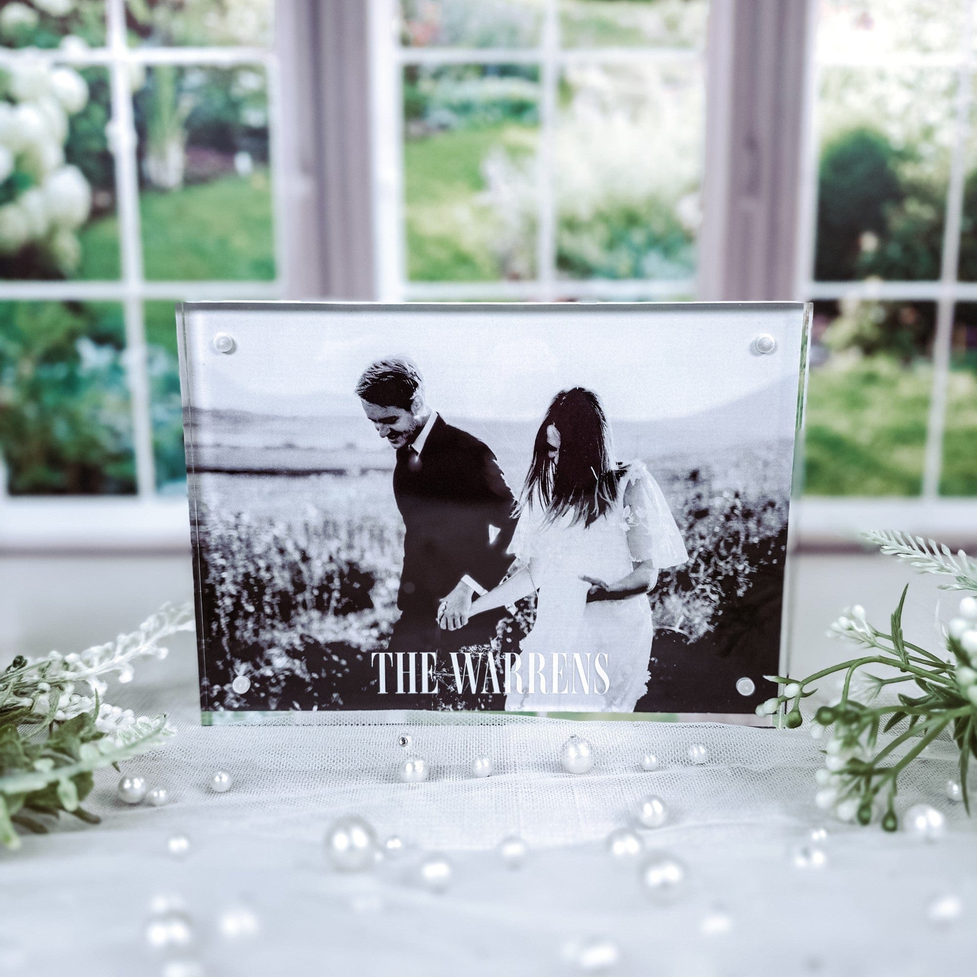 A personalized clear acrylic photo block, secured by magnets, displaying a black and white image of a couple, perfect as wedding or anniversary decor.