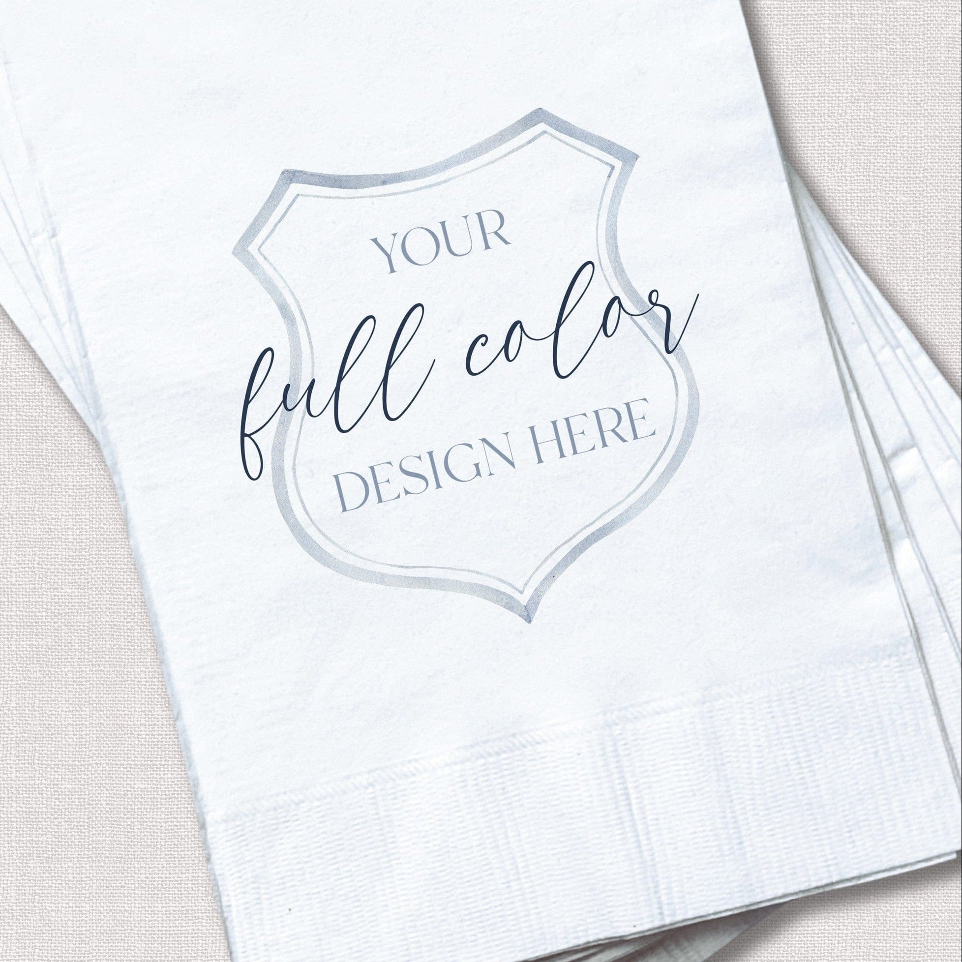 A stack of white paper napkins featuring a customizable shield-shaped area for a full-color design, perfect for personalized wedding or event decor.