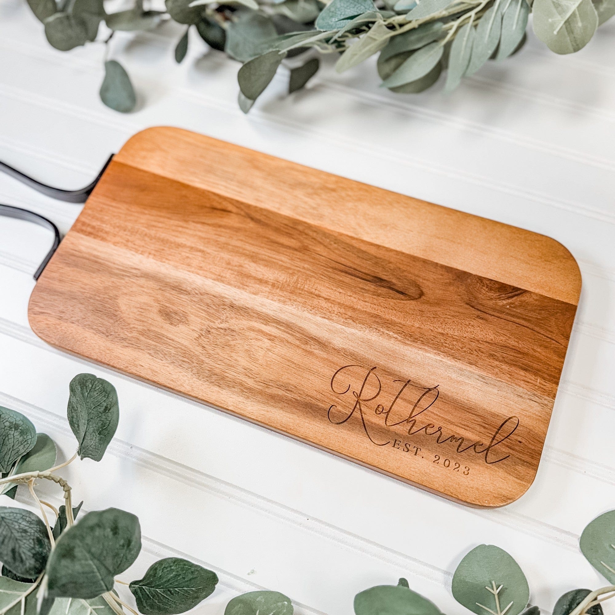 A personalized rectangular wooden serving board with black metal handles, suitable as a wedding or housewarming gift.