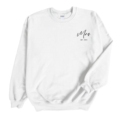 A cozy white cotton blend crewneck sweatshirt featuring a custom black graphic on the chest, perfect for a bridal celebration.