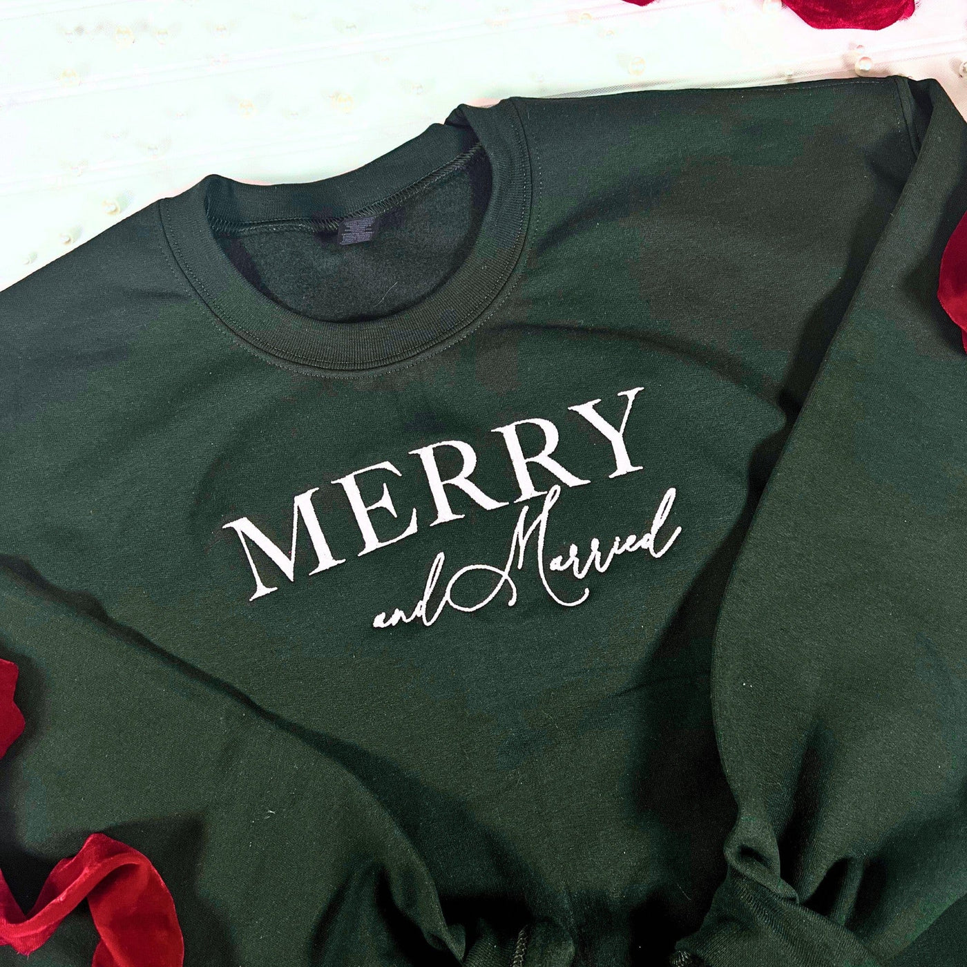 A dark green fabric sweatshirt featuring white decorative lettering, suitable for a winter wedding celebration or bridal event.