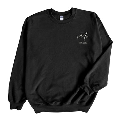 A black crewneck sweatshirt featuring white script embroidery on the chest, made from cozy fabric and designed for wedding-related celebrations.