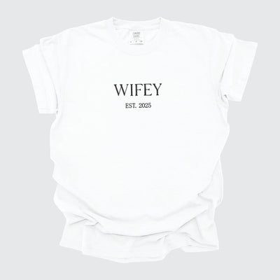 A neatly folded white short-sleeved t-shirt crafted from comfortable fabric, ideal for bridal events.