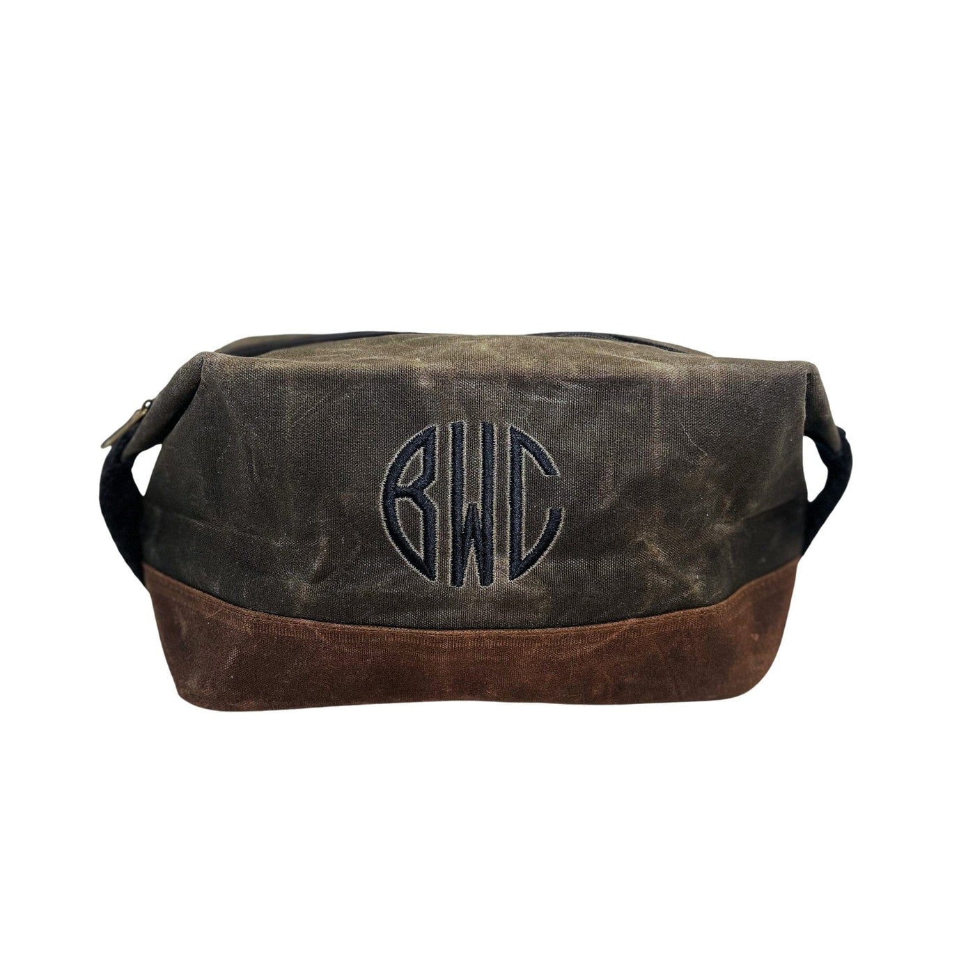 A two-tone personalized waxed canvas toiletry bag with a dark upper and brown base, featuring an embroidered design for carrying travel essentials.