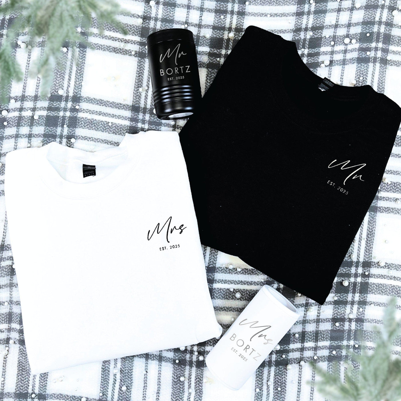 A coordinated bridal gift set featuring a black and a white crewneck sweatshirt made from soft fabric, alongside a black and a white insulated tumbler, perfect for commemorating a wedding.