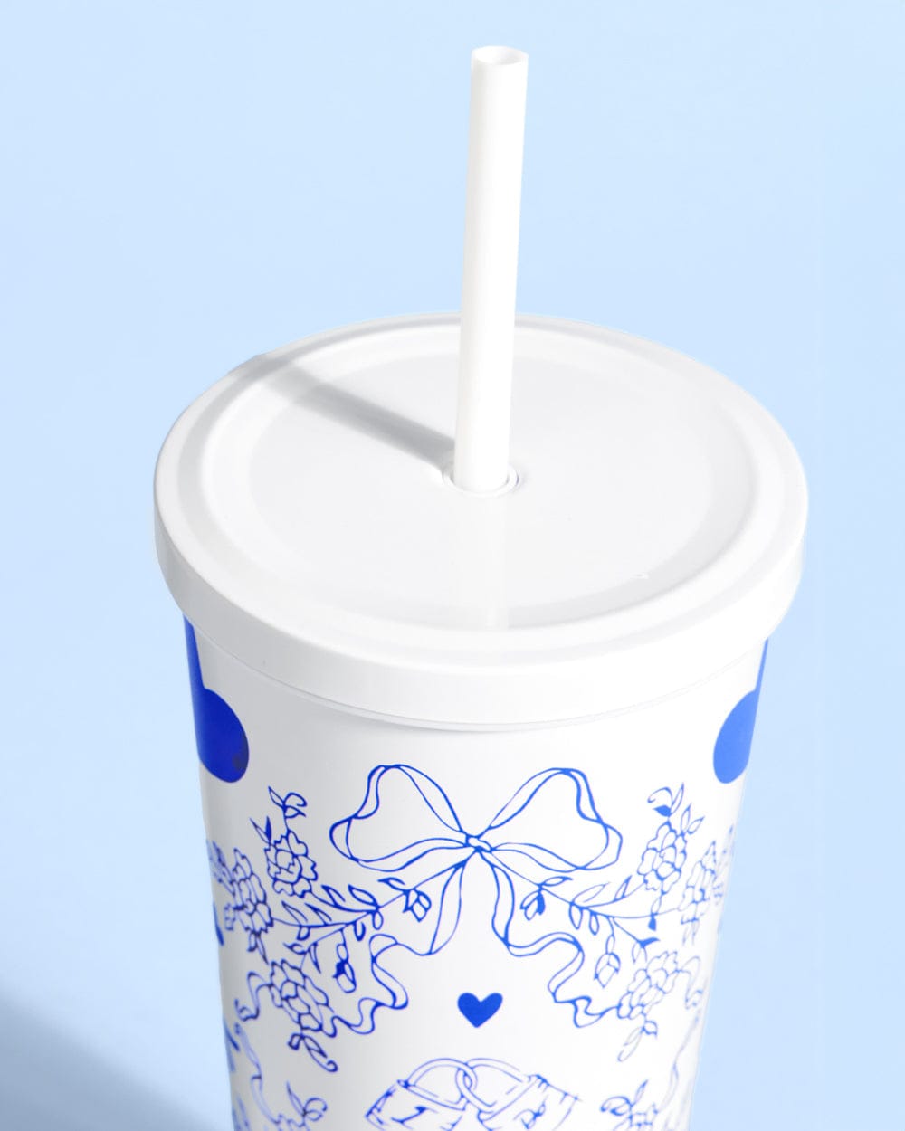 White 24 oz tumbler with blue floral bow and heart design, white lid and straw