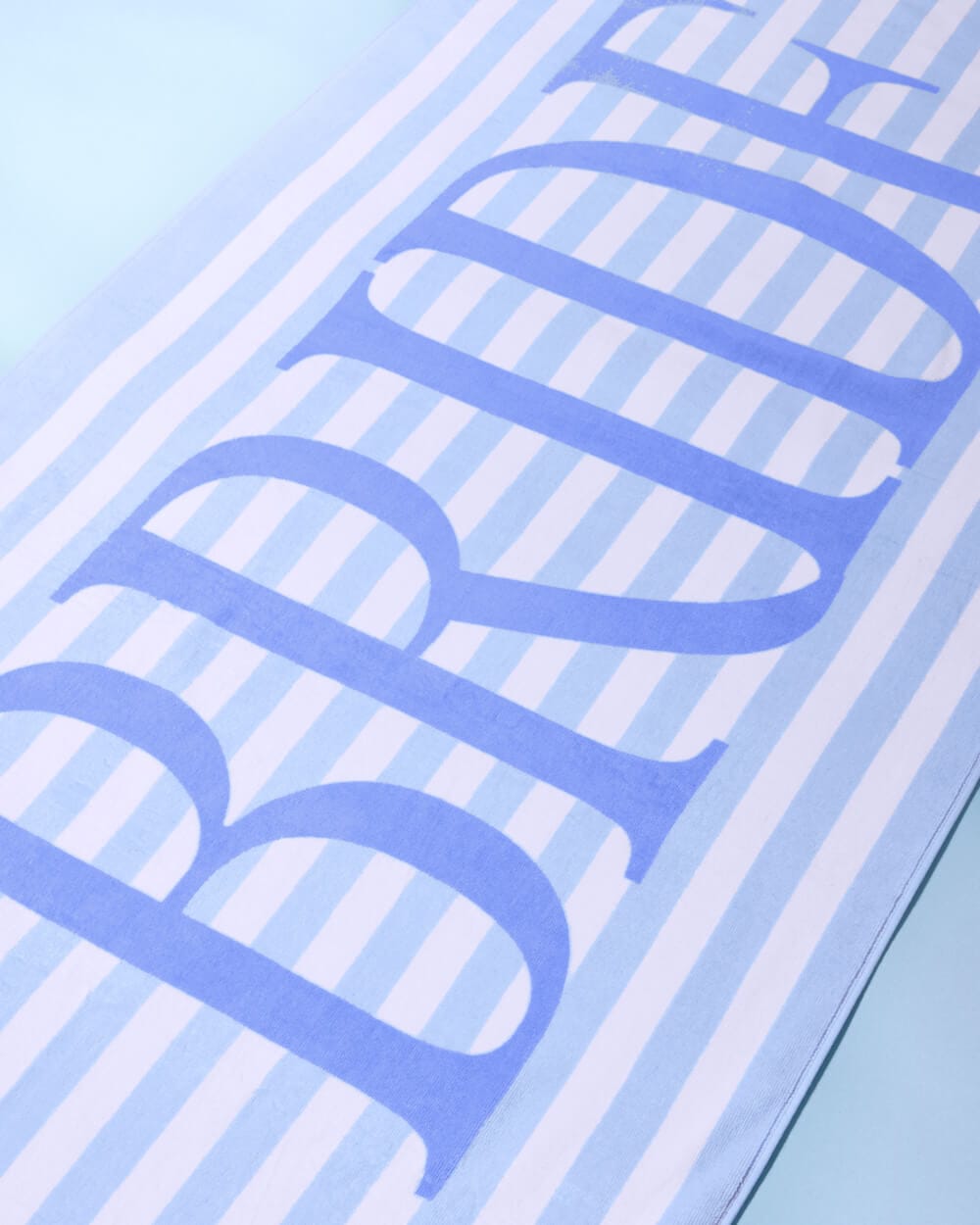 Coastal Bride beach towel with blue and white stripes and bold blue text design